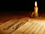 carol sheet music with lit candle on table