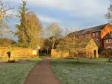 frosty park area with path through gap in brick wall