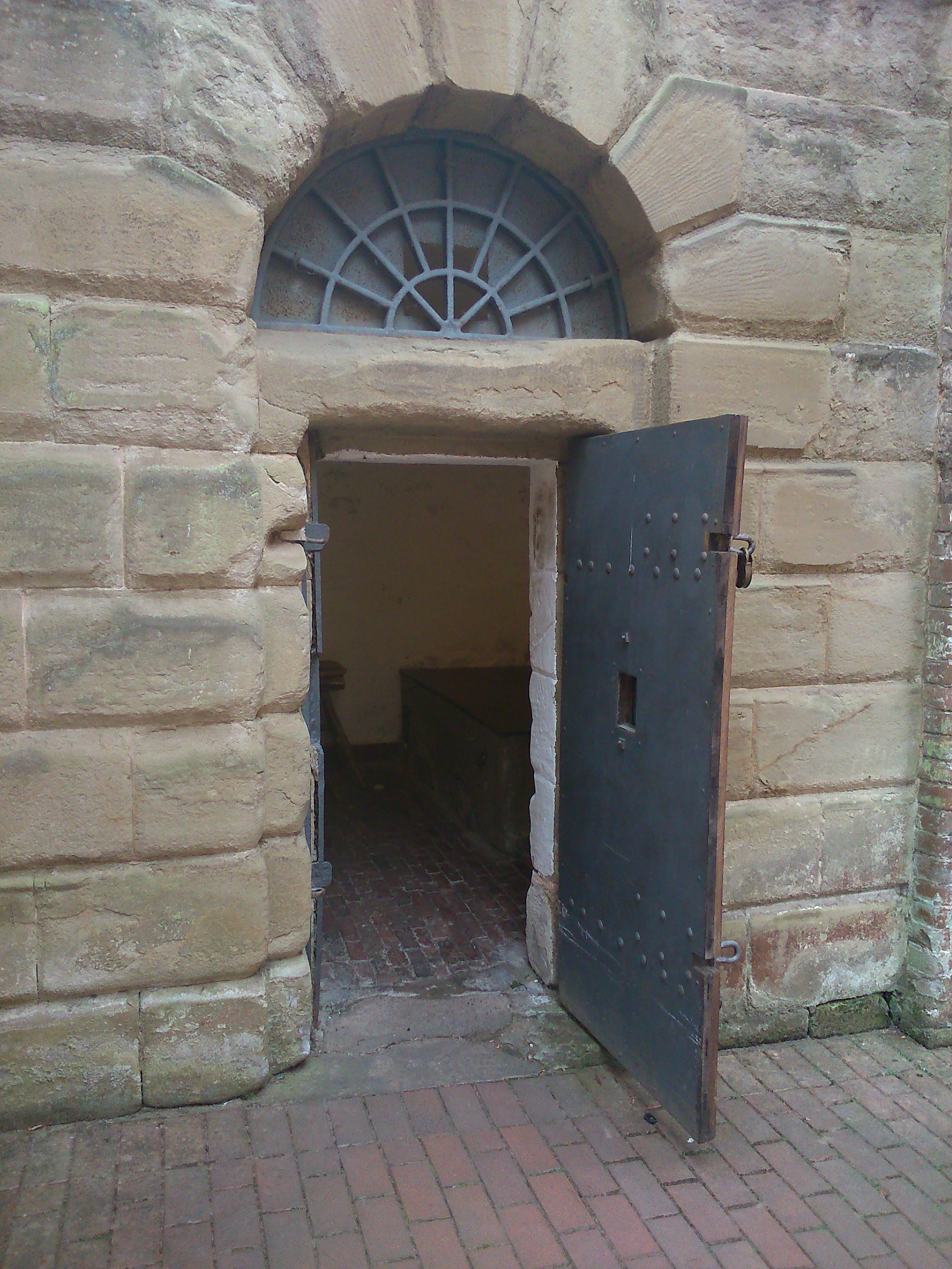 metal cell door in stone arch an old jail cell is partly visible through the door