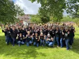 large group of people in green open space smiling at camera