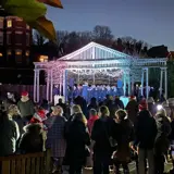 a group of people gathered together inoutdoor theatre singing Chrostmas carols at nighttime 