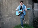 Guitar player leaning against wall