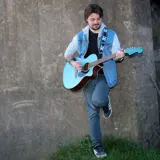 Guitar player leaning against wall