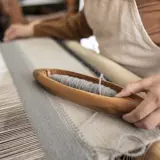 a person holding an embroidery hoop and sewing
